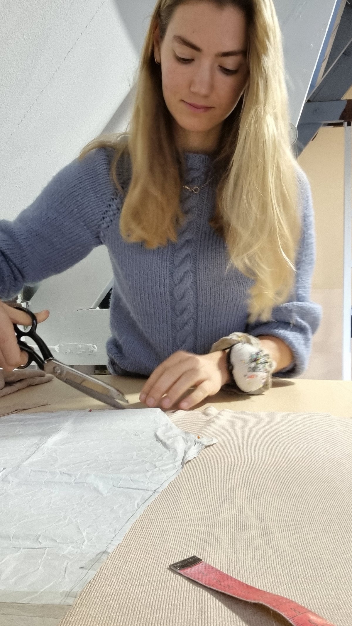 Lara knipt met een grote schaar een patroon uit op de snijtafel