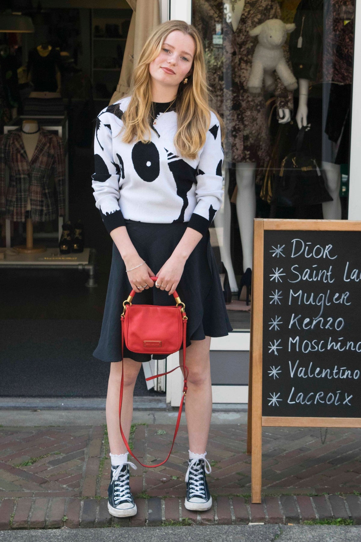 Ballet wrap skirt in zwart, gestyled met een wit-zwarte trui, rode tas en sneakers
