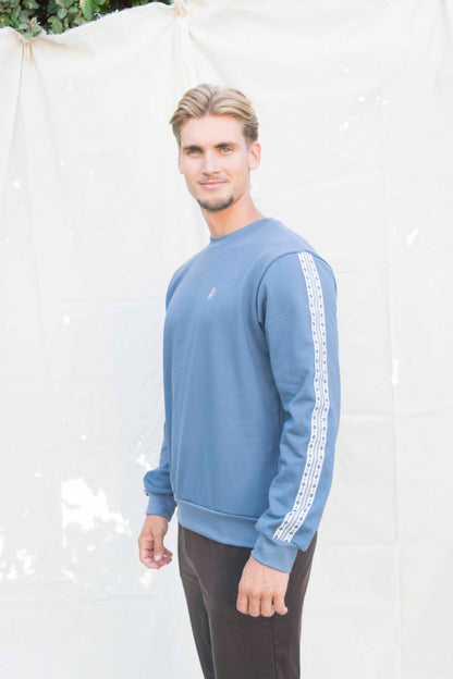 Basic sweater unisex in middenblauw met schortenbont-band op de mouwen, vooraanzicht