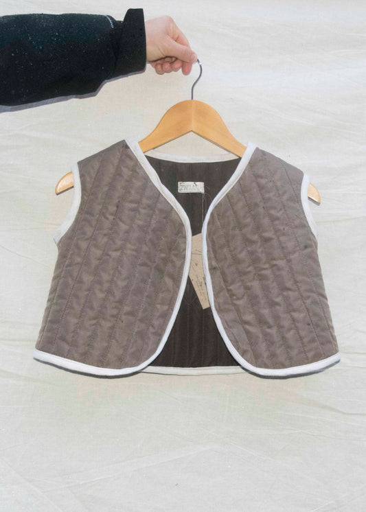 Mini gilet taupe gequilt met ongebleekt linnen biesje, vooraanzicht op hanger