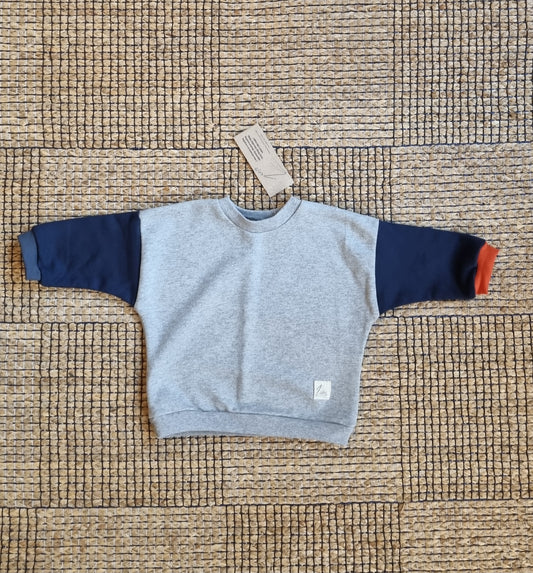 Mini remix sweater lichtgrijs met donkerblauwe mouwen en oranje boorden, vooraanzicht