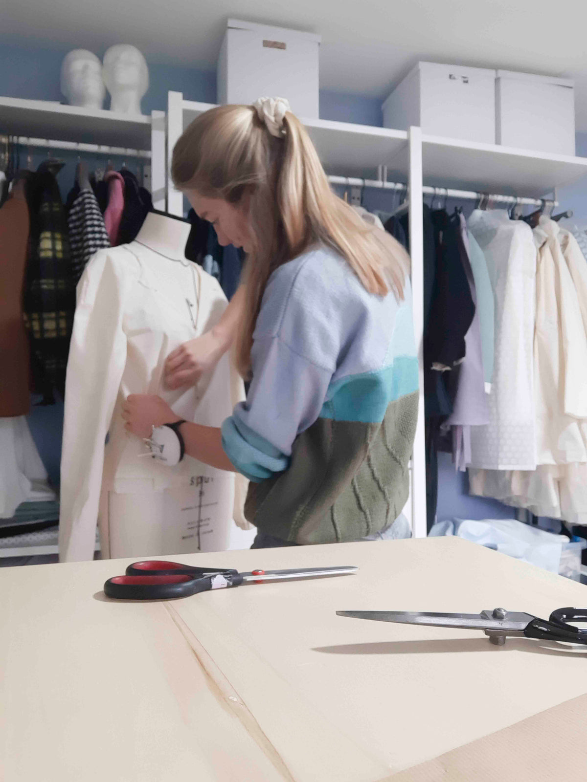 Lara past een kledingstuk op een paspop in haar atelier