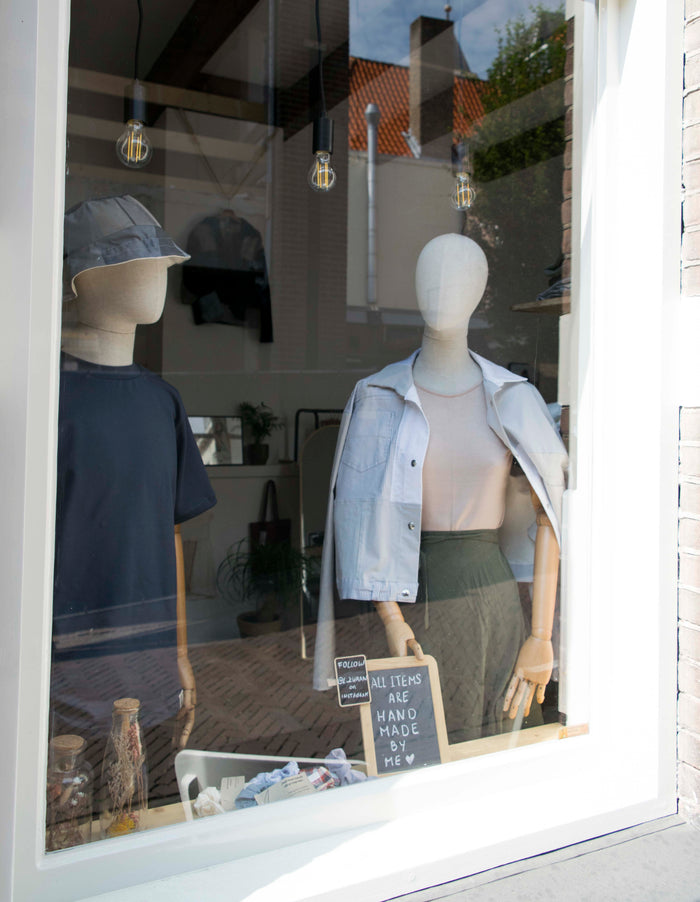 Etalage van de ZWAAN store met twee paspoppen in ZWAAN-kleding en een krijtbordje